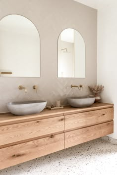 there are two sinks in the bathroom with mirrors on the wall above them and an oval mirror