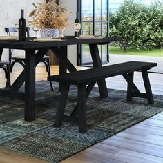 a dining room table with two benches in front of it and an area rug on the floor