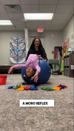 a young child laying on top of a blue ball in the middle of a room