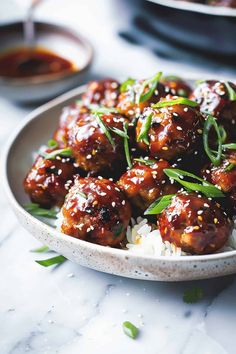 a white plate topped with meatballs covered in sesame seeds and garnished with green onions