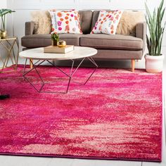 a living room with a couch, coffee table and pink rug