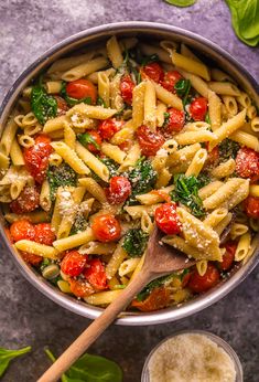 a pan filled with pasta, tomatoes and spinach