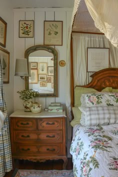 a bed room with a neatly made bed next to a dresser and mirror on the wall