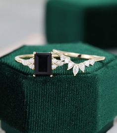 a black diamond ring sitting on top of a green velvet box