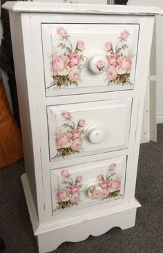 a white dresser with pink flowers painted on the drawers and knobs in front of it