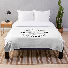 a white bed sitting on top of a wooden floor next to a potted plant