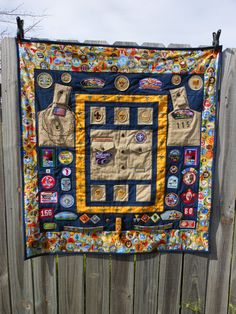 a quilted wall hanging on a wooden fence with patches and buttons all over it