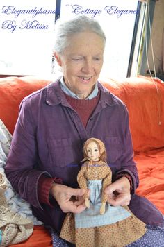 an older woman sitting on a couch holding a doll