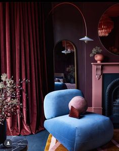 a blue chair sitting in front of a fire place next to a mirror on a wall