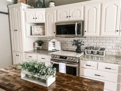 a kitchen with white cabinets and wood counter tops, an oven, microwave and dishwasher