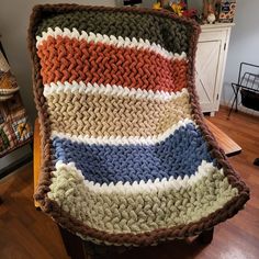 a crocheted blanket sitting on top of a wooden table next to a chair