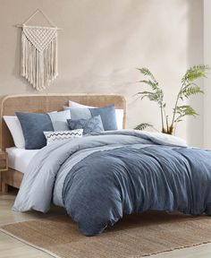 a bed with blue comforters and pillows in a room next to a potted plant