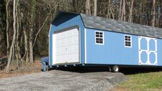 a small blue house sitting in the middle of a wooded area with a car parked next to it