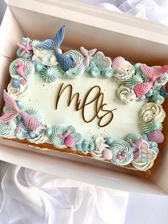 a decorated cake in a box with the letter m and seashells on it