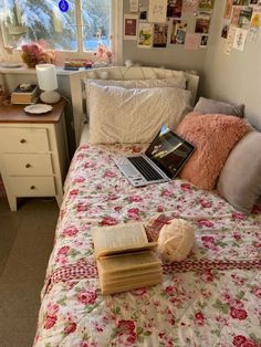 an open laptop computer sitting on top of a bed next to pillows and blankets in a bedroom