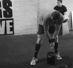 a man bending over with his knee on top of a bucket