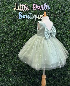 Our enchanting Knee Length flower girl dresses are sure to turn heads! This beautiful elegant sophisticated dress is handmade, the bodice consists of Sage Bridal Satin with a sowed in sash at the waist, the back of the dress consists of an open V-back with a hidden zipper. The big bow is detachable. The skirt consists of 4 sage layers of tulle with the top layer consisting of Ivory Tulle with sowed in Ivory pearl beads. The fifth layer is made of lining with crinoline for fullness.  This dress i Elegant Green Sleeveless Tutu Dress, Fitted Sleeveless Pageant Dress For First Communion, Fitted Tutu Dress With Bow For Wedding, Green Princess Dress With Bow, Fitted Sleeveless Pageant Dress For Baptism, Fitted Green Dress For Baptism, Elegant Green Tutu Dress For Pageant, Fitted Sleeveless Ball Gown For First Communion, Junior Girl Dresses