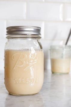 a glass jar filled with liquid sitting on top of a counter next to a spoon