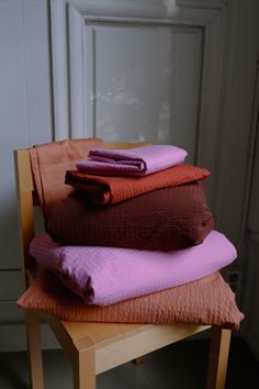 a stack of folded towels sitting on top of a wooden chair