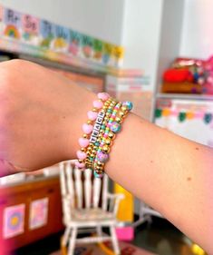 a woman's arm with two bracelets on it and a chair in the background