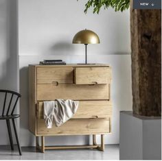 a wooden dresser sitting next to a black chair and a lamp on top of it