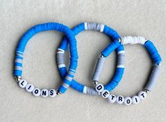 These handmade stackable bracelets get you ready for game day!  Price includes THREE bracelets. If you want to customize your stack, please message me! Made with blue, silver and white Heishi beads, seed beads and high quality stretchable string for durability. Ships within the normal 1-3 business days.  Size 6 fits kids, size 6.5 fits small wrists and size 7 fits most. If a larger size is needed, please let us know (measure wrist tightly with no slack, adding .5" to find your perfect fit). Not seeing the colors or style you're looking for? Message for custom orders at no additional charge. CARING TIPS: These bracelets are made with quality stretch cord, but are still delicate. Please be careful when taking them on and off. Rolling is best. For longevity, do not expose your jewelry to wate Football Bracelet, Clay Bracelets, Detroit Lions Football, Lions Football, Sports Bracelet, Clay Bracelet, Sport Armband, Bracelets Set, Bracelet Ideas