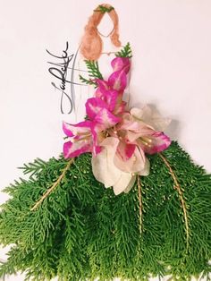 pink flowers and greenery are hanging on the wall in front of a white background