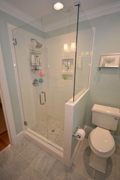 a white toilet sitting next to a shower in a bathroom on top of a tiled floor