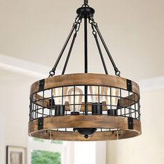 a wooden chandelier hanging from the ceiling in a room with white walls and windows