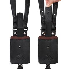 a hand is holding two black suspenders