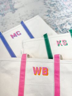 three white bags with pink and green handles are sitting next to each other on the floor