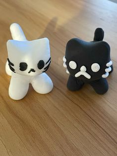 two small black and white toys sitting on top of a wooden table