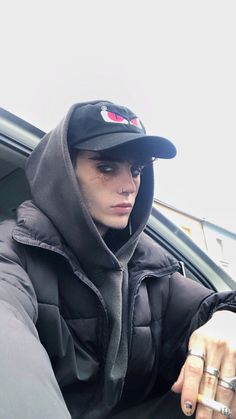 a person sitting in a car wearing a hoodie and holding onto a cell phone