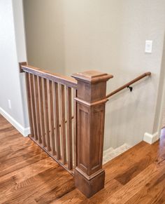 a wooden bannister in an empty room with hard wood floors and white walls