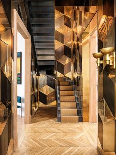 an open door leading to a room with wooden floors and walls covered in gold geometric tiles