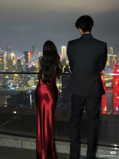 a man and woman looking out over the city at night