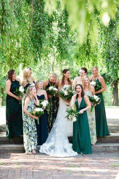 a group of women standing next to each other in front of green and gold dresses