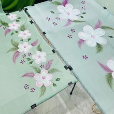 two green tablecloths with pink and white flowers on them are sitting next to each other