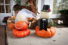 two pumpkins sitting on top of each other in front of a house with a bride and groom