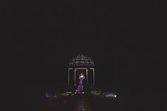 a couple standing in front of a gazebo at night