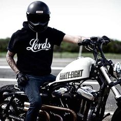 a man sitting on top of a motorcycle wearing a helmet and holding the handle bars