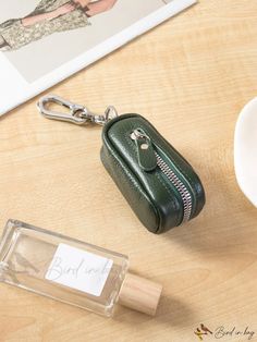 a green purse keychain sitting on top of a table next to a cup