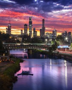 the city skyline is lit up at night, with boats on the river in front