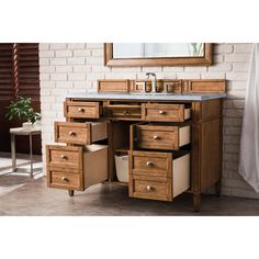 a bathroom vanity with drawers and a mirror on the wall above it, in front of a brick wall