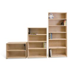 three wooden bookshelves with various types of books on them and one is empty