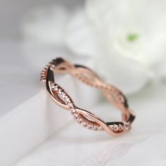 a rose gold wedding ring with diamonds on the inside and outside, sitting next to a white flower