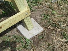 a wooden bench sitting on top of a cement block in the middle of some grass