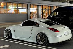 a white sports car parked next to a black truck