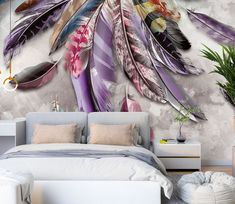 a bedroom with a bed and large wall mural featuring feathers on the wall, along with a plant