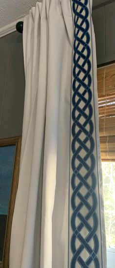 the curtains are hanging in front of a window with blue and white designs on them